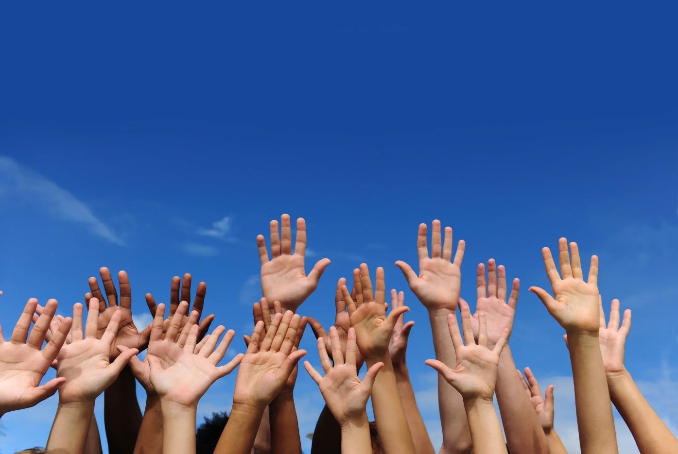 raised hands with blue sky in the background